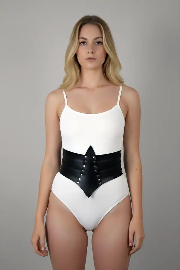 Black faux leather waist cincher corset belt with silver studs and pointed front panel worn over white bodysuit