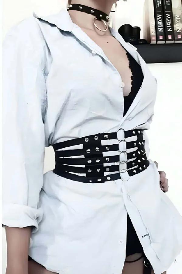 black faux leather wide waist belt with silver dome studs and three O-rings worn over a white shirt